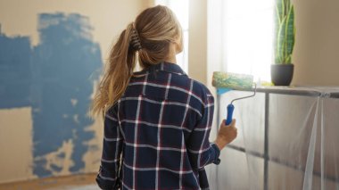 Kadın modern evdeki duvarları, doğal ışıkla çevrili yuvarlaklarla boyuyor. Taze bir yaşam alanı atmosferi yaratıyor. Yenilemeyi ve yaratıcı ifadeyi yansıtıyor..