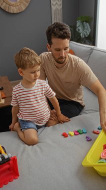 Baba ve oğul, sıcak bir oturma odasında renkli alfabe oyuncaklarıyla oynayıp sıcak bir aile anını içeride göstererek kaliteli zaman geçiriyorlar..