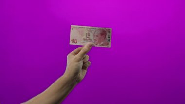 İzole edilmiş mor arkaplan üzerinde el ele tutuşma Türk lira banknotu, belirgin para gösterme.