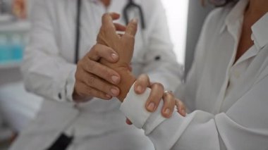 Klinikte kadının bileğini muayene eden doktor, profesyonel iç ortamlarda tıbbi danışmanlık ve özen gerektiren sağlık hizmetleri sunuyor..