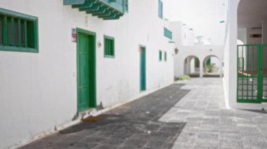 Lanzarote, İspanya, kanarya adalarında güneşli bir günde yeşil kapıları ve pencereleri olan dış odaksız beyaz evler.
