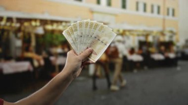 Elinde Danimarka kronu banknotları olan bir adam şehir restoranının terasında..