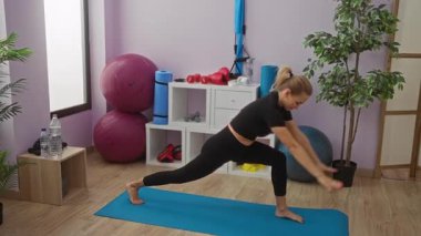 Spor salonunda egzersiz topları ve ekipmanlarıyla yoga minderinde uzanan, kapalı spor merkezinde spor yapan, dengeyi korumaya ve formda kalmaya odaklanmış bir kadın..