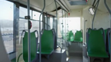 Yeşil koltuklu boş bir otobüs içi ve yumuşak gün ışığında temiz ve modern bir toplu taşıma aracının kapalı alanda yakalandığını gösteren bir arka plan..
