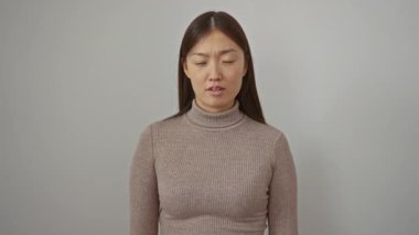 İzole edilmiş beyaz bir arka plana bakan, kendine güvenen, bej balıkçı yaka giyen, yön kavramını vurgulayan ve odaklanan bir kadın..