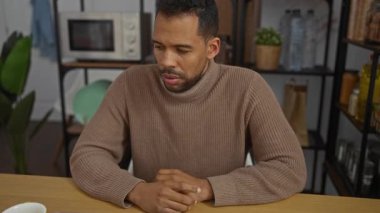 Modern ofis ortamında çalışan genç bir adam şık dekorasyonlar ve kapalı mekanlarda çalışırken dizüstü bilgisayar kullanıyor ve gündelik giysiler giyiyor.