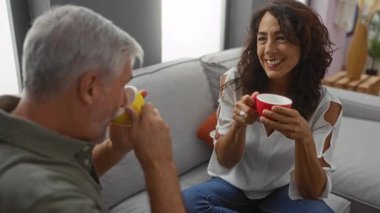 Oturma odasında kahve fincanlarının üzerinde gülümseyen bir çift rahatlık ve arkadaşlık öneriyor..