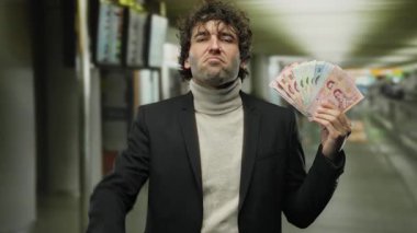 Havaalanı terminalindeki İspanyol adam Tayland Baht 'ı ciddi bir jestle tutuyor..