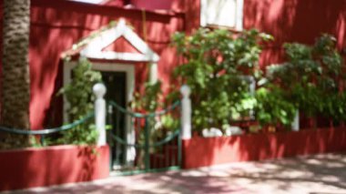 Parlak güneş ışığında yeşil ve çitli canlı kırmızı bir evin arka planı bulanıktı.