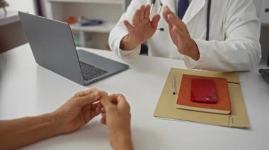 Doktor, bir tıp kliniğinde, masada dizüstü bilgisayarı ve akıllı telefonu olan hastalara danışmanlık yaparak, sağlık hizmetlerinin etkileşimini vurguladı..