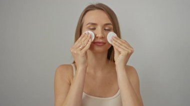 Pamuk pedlerle cilt bakımı yapan bir kadın izole edilmiş beyaz arka planda güzellik ve sağlık pratiği yapıyor..