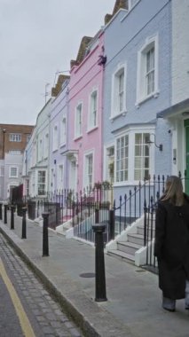 Chelsea Londra 'da bir caddede renkli evler boyunca yürüyen kadın canlı mimari ve şehir cazibesini yakalıyor..