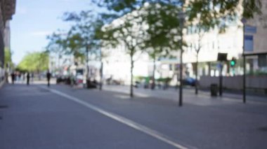 Marsilya 'da insanların yürüdüğü bulanık bir sokak, yol boyunca ağaçlar, ve yumuşak bokeh ışıklandırması..