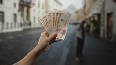 Güney Kore 'nin el ele tutuşması, açık şehir sokak ortamında para kazandı. Arka planda bir adam, canlı bir para birimi ve şehir hayatı tasviri yaratıyor..