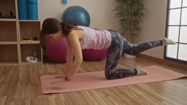 Beden eğitiminde yoga yapan bir kadın. Arka planda egzersiz topları, denge ve esneklik..