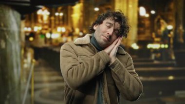 Şehirde bir sokakta genç bir İspanyol adam elleriyle uyku jesti yapıyor. Geceleri sakin ve sakin bir şehir ortamında yakalanıyor..