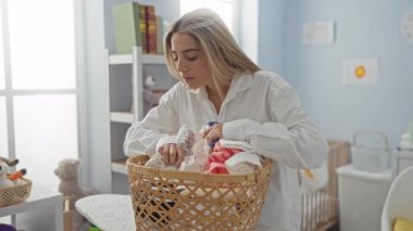 Genç bir kadın iç çamaşırları parlak bir evde katlıyor..