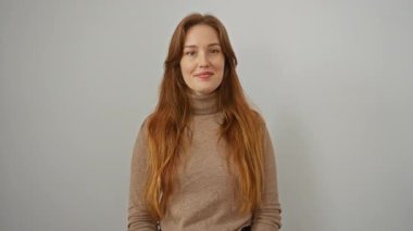 Beyaz arka planda gülümseyen bir kadın iyimserliği ve ifadedeki memnuniyeti yansıtan minimalist bir ortamda kendine güven ve olumlu bir jest sergiliyor..