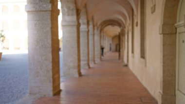 Üniversite kampüsündeki bulanık kemerli koridor, eski taş mimariyle, arka plan ve bokeh etkisine sahip, açık hava akademik ortamı öneriyor..