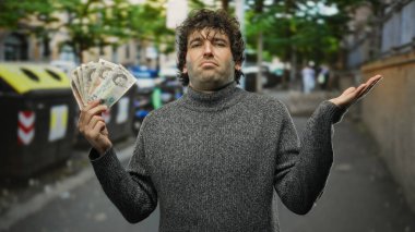 Dışarıda dikilen bir adam çöp konteynırlarının yanında İngiliz sterlini tutuyor. Arka planda ağaçlar ve binalar konusunda kafası karışmış ve kararsız görünüyor..