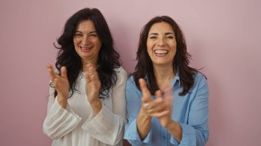 Pembe bir duvarın önünde sevinçle alkışlayan kadınlar, sevgi, dostluk, aile ve birlikteliği simgeleyen, orta yaşlı kız veya arkadaşları olan, mutluluk ve samimiyet gösteren,.