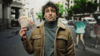 Türk lira banknotlarını elinde tutan adam hareketli bir şehir caddesinde, açık bir şehir ortamında finansal büyüme ve başarıyı vurguluyor..