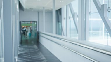 Bulanık gezginler, aydınlık, modern bir iç mekan ve uzak Bokeh arkaplanının net bir görüntüsü ile çözünmüş bir havaalanı terminalinde yürüyorlar..