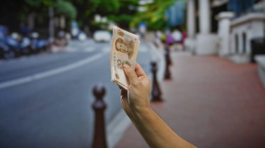 Şehir merkezinde Çin Yuan banknotları tutan bir adam, sokak ortamında iş ve para değişimi tasvir ediyor.
