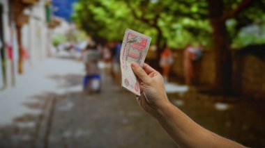 Bulanık şehir hayatı, açık hava ticaret ve para değişimi ile çevrili, hareketli bir şehir caddesinde, uae dirham banknotları tutan adam.