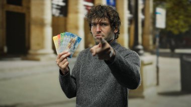 Bir şehir caddesinde elinde İsviçre frangı banknotları tutan İspanyol bir adam, canlı bir şehir ortamında finansal veya ekonomik bir konsept öneriyor.