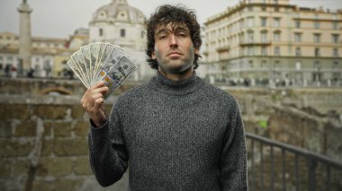 Bir şehir caddesinde Amerikan banknotlarını elinde tutan İspanyol bir adam, ABD 'deki ikonik bir şehir zeminine karşı güven ve zenginlik sergiliyor..