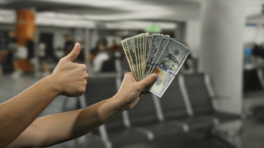 Havaalanı ortamında Amerikan dolarlarını tutan adam başarıyı ve seyahate hazır olmayı sembolize ediyor..