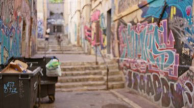 Gecekondu mahallesinde canlı grafiti ve odağından çıkarılmış çöp kutularıyla bulanık bir sokak cesur bir açık hava ortamının özünü yakalıyor..