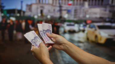 Yoğun bir şehir caddesinde İsviçre Krona 'yı elinde tutan bir adam. Bir sıra taksi ve bulanık şehir geçmişi modern iş ortamını ima ediyor..