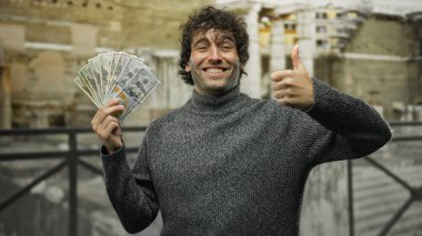 İspanyol asıllı bir adam şehir sokaklarında Amerikan dolarlarını tutuyor, başparmağıyla güvenle gülümsüyor, başarıyı ve finansal refahı temsil ediyor..