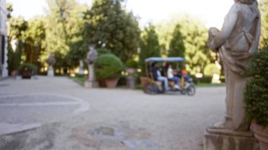 Villa borghese bahçesinde bisiklet süren, yeşillikleri, heykelleri ve İtalyan ortamında sakin atmosferi vurgulayan, heykelleri olan açık hava manzarası..