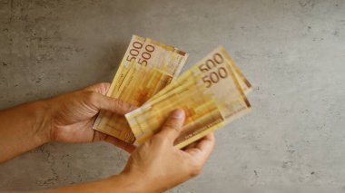 Man's hands holding norwegian kroner money bills on a concrete background, indicating financial transactions or currency exchange