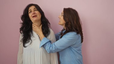 Kadınlar pembe bir duvara yaslanarak bir diğerinin boynunu tutarak etkileşime girerler. Olgun kız kardeşler ya da güçlü duyguları olan arkadaşları dramatik bir pozda resmederler..