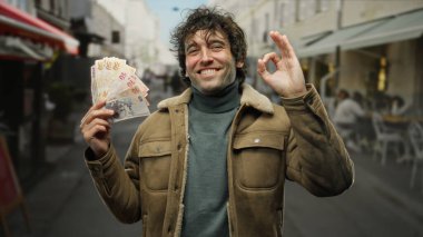 Elinde Türk lirası banknotları tutan İspanyol bir adam kalabalık bir caddede açık havada iyi bir jest yapıyor..