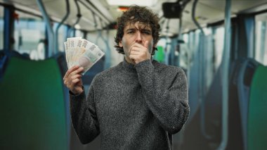 İspanyol adam, Czech Koruna banknotlarını kapalı bir otobüste tutuyor. Düşünceli ve düşünceli görünüyor..