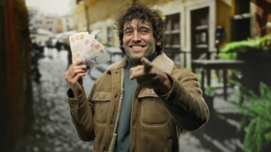 İspanyol adam, elinde Türk lirası banknotları tutarken kameraya gülümseyip işaret ediyor..