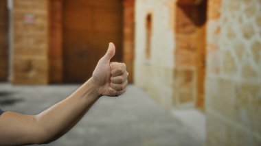 Şehir dışındaki bir sokak ortamında, şehir ortamında, bulanık tarihi mimari geçmişi olan, pozitifliği ve onayı vurgulayan bir adam elini kaldırıyor..