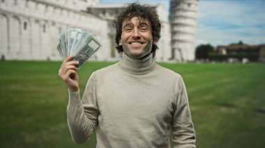 Gülümseyen adam güneşli bir günde sidik kulesinin önünde Bangladeş Taka 'yı tutuyor. İkonik bir italyan şehrinde uluslararası para birimi sergiliyor..