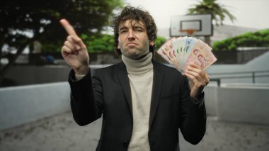 Bir şehir caddesinde İspanyol bir adam Thai banknotlarını elinde tutuyor. Bir parmağı uzatılmış, bu da para kavramını gösteriyor..