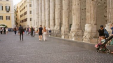Roma 'nın eski kasabasındaki kaldırım taşlı bir sokakta yürüyen bulanık insanlar. Parlak bir günde tarihi binalar ve mimari atmosferi dağılmış..