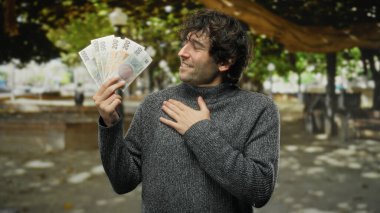 İspanyol asıllı bir adam, Czech Koruna 'nın banknotlarını elinde tutuyor. Czech cumhuriyetindeki sakin bir park geçmişine karşı koyuyor. Bir anlık finansal başarı yakalıyor..