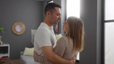 Kadın ve erkek sıcak bir oturma odasında sevgi dolu bir şekilde kucaklaşıp evdeki yakın ilişkilerini yakalıyorlar..