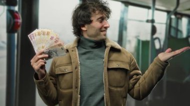Otobüsün içinde elinde Türk lirası banknotları tutan adam güvenle gülümsüyor, kapalı bir ortamda para gösteriyor, zenginlik ve seyahat temalarını iletiyor..