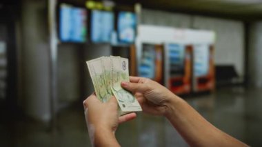 Havaalanı terminalinde Singapur doları tutan adam, kapalı alanda yatırım ve döviz kuruna odaklı seyahat finansmanı öneriyor..