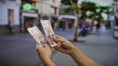 Bir şehir caddesinde açık havada İzlanda banknotları sayan bir adam, kentsel bir ortamda yatırım ve para değişimi sembolize ediyor.